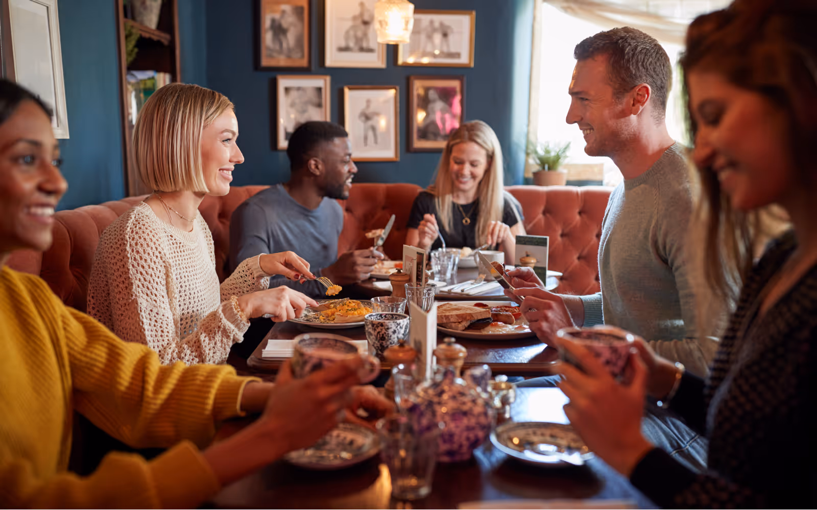 Smiling diners in a crowded UK restaurant benefiting from a loyalty rewards program